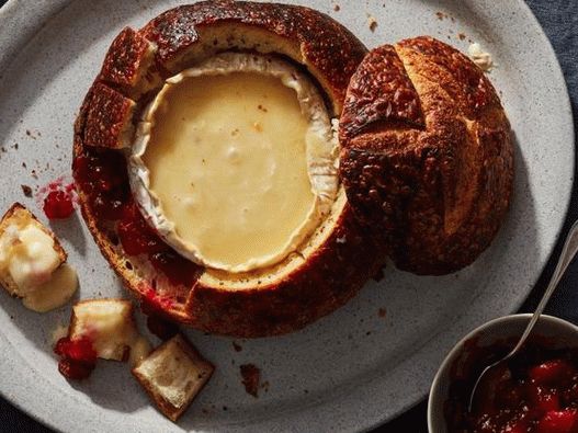 Foto Uma tigela de pão recheada com queijo brie e molho de cranberry