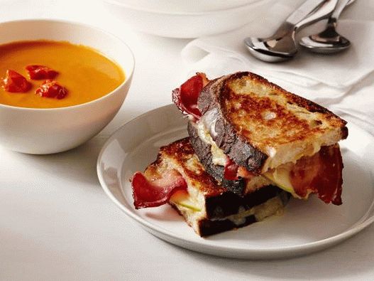 Foto sopa de creme de tomate assado e um sanduíche com queijo e bacon