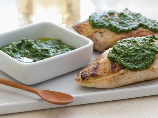 Frango grelhado em uma panela com pesto de espinafre e pinhões