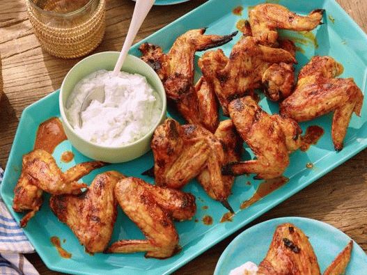Foto de asas de frango grelhado em molho picante de chipotle e um molho de queijo azul e iogurte