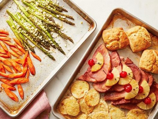 Foto jantar de Páscoa de presunto, legumes e um pão em duas assadeiras