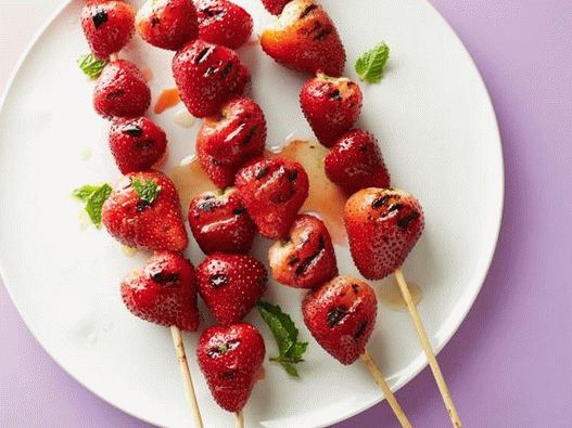Foto espetos de morango grelhados com molho de limão e menta
